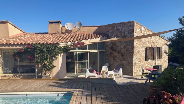 A poolside area with a wooden deck, a swimming pool, and outdoor seating including lounge chairs and a table. - house / villa - 5 rooms - 10/14 persons (Lumio)