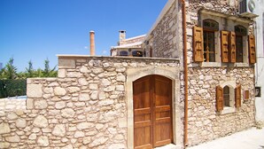 A stone building with a large wooden door and arched windows. - Blue Paradise villa With Pool And Jacuzzi For 5 People (rethymno)