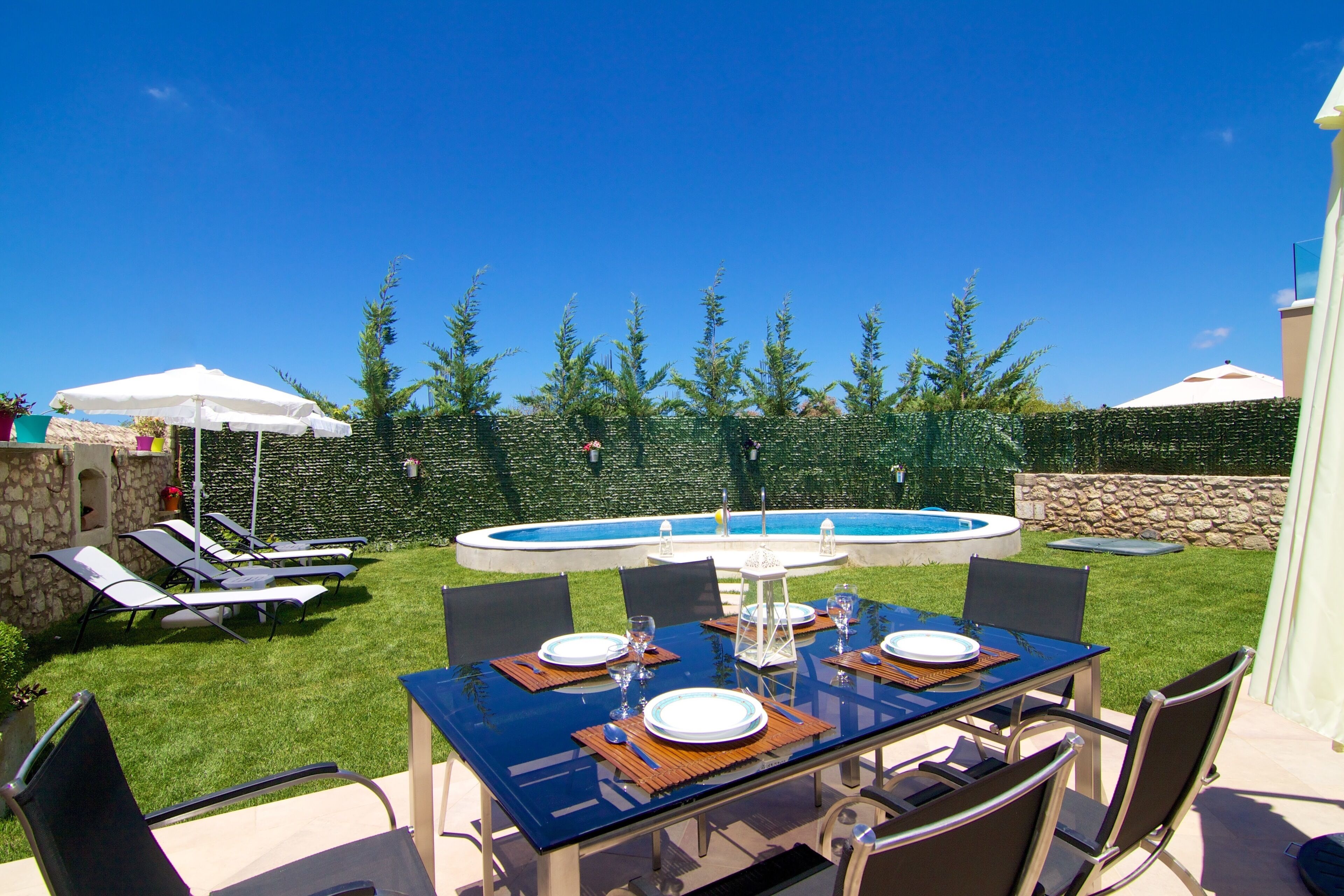 Ein Garten mit Pool, einem Esstisch für vier Personen und Liegestühlen.