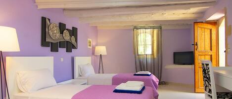 Une chambre d’hôtel avec deux lits, une télévision, une porte en bois et une fenêtre avec des rideaux.