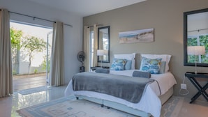 A bedroom with a bed, bedside tables, a mirror, and a window with curtains.