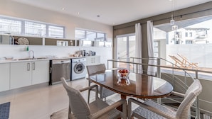 A modern kitchen with white cabinets, a stainless steel dishwasher, and a built-in washing machine.