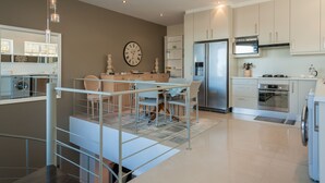 A modern kitchen with a dining area, stainless steel appliances, and a staircase with a railing.