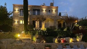 A stone building with a pool, outdoor seating, and illuminated lights.