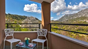 A balcony with two white chairs and a table, overlooking a mountainous landscape with a clear sky. - Lux villa,  heated infinity salt water pool, sauna, whirpool, close to the sea. (Smolonje)