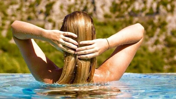 A person sitting in a swimming pool with their hands behind their head. - Lux villa,  heated infinity salt water pool, sauna, whirpool, close to the sea. (Smolonje)