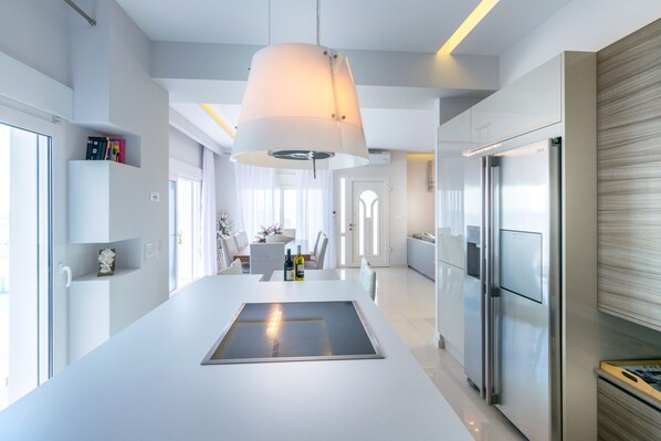 Cocina moderna con una isla central, electrodomésticos de acero inoxidable y una lámpara colgante.