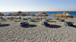 A beach with thatched umbrellas and sun loungers.