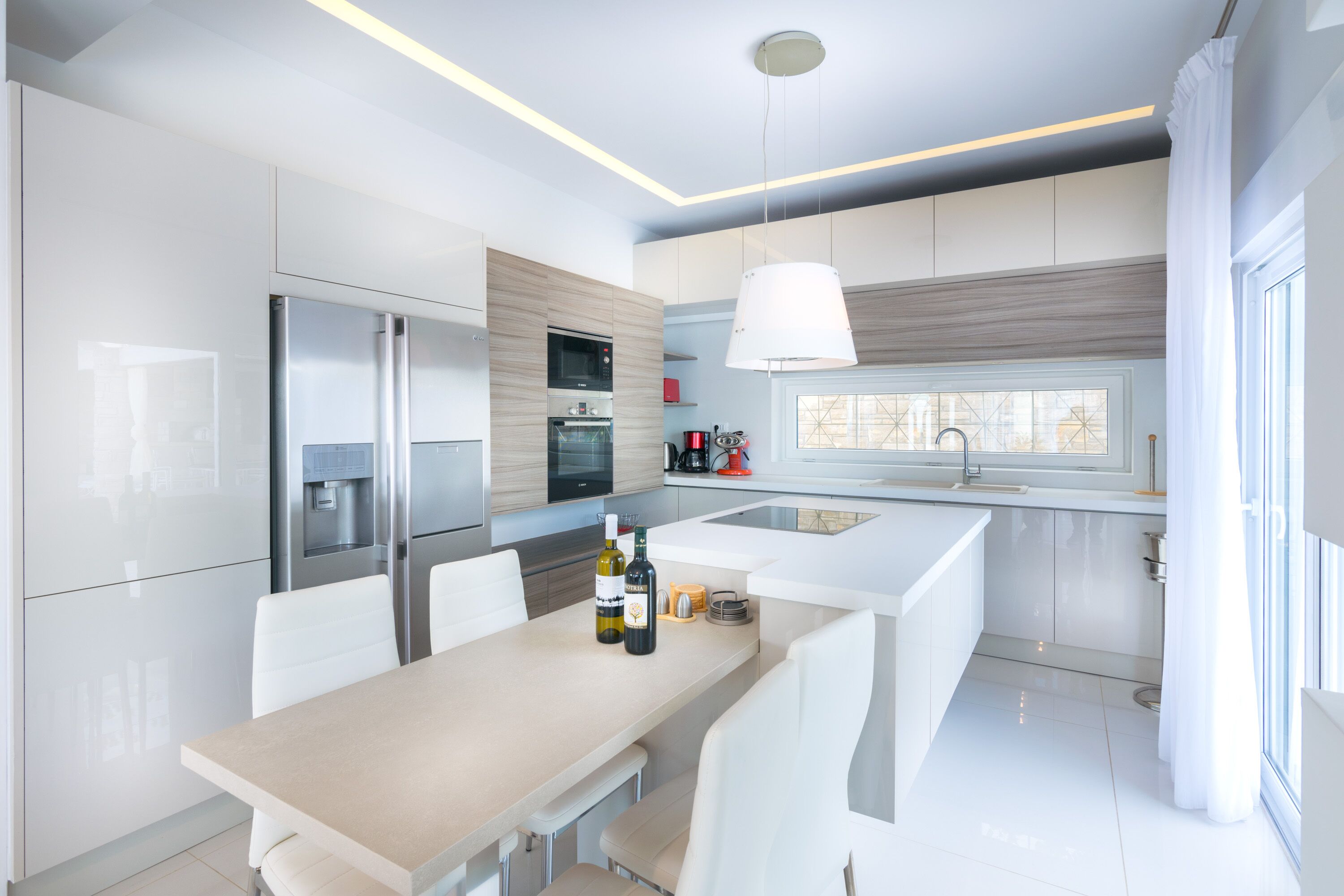 A modern kitchen with white cabinetry, stainless steel appliances, and a central island with seating.
