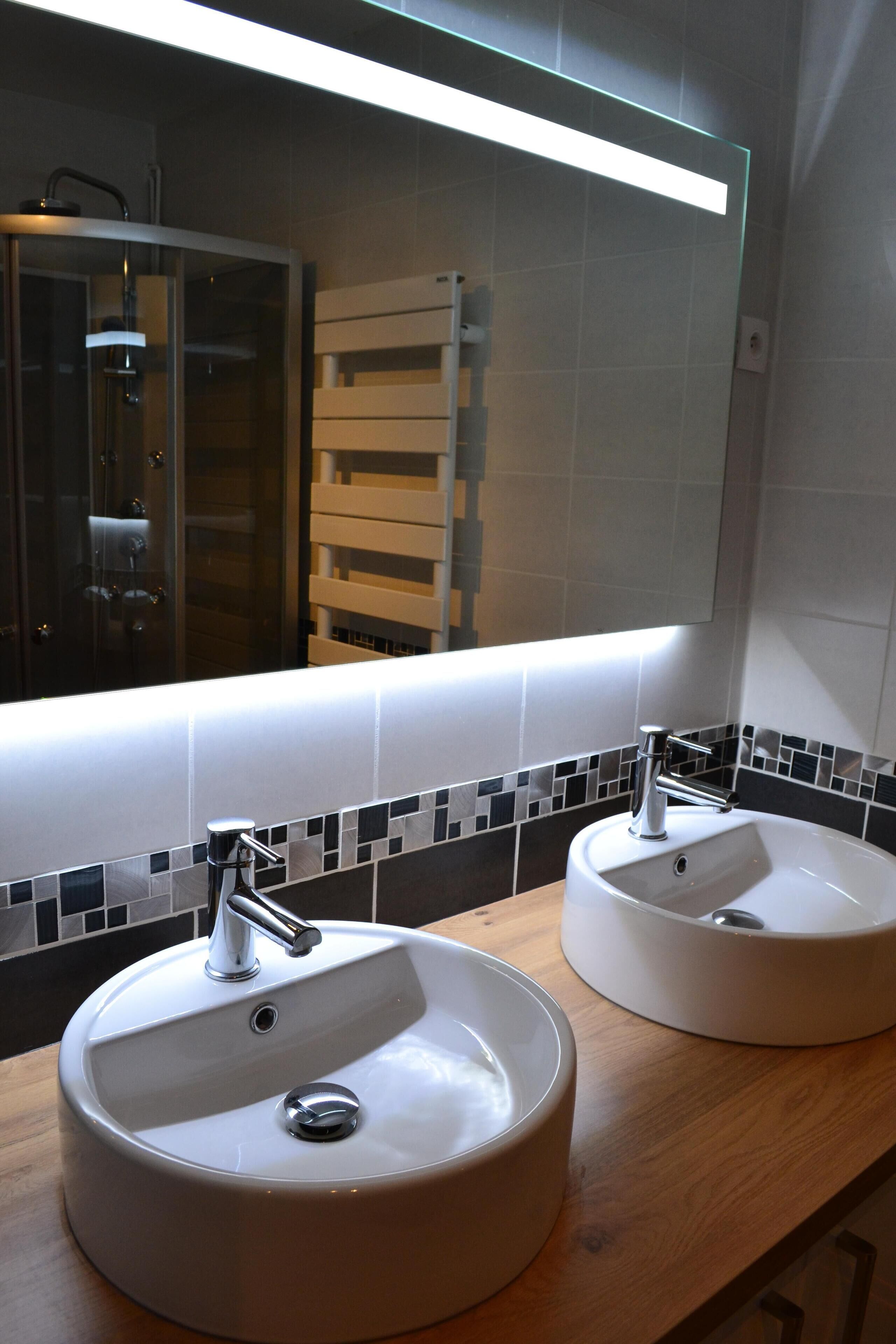 Une salle de bain avec deux lavabos, un miroir et un porte-serviettes.