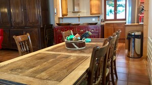 Un espace repas comprenant une table en bois, des chaises et un grand panier décoratif placé au centre.