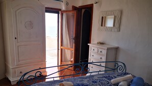 Une chambre à coucher comprenant un lit, une commode, un miroir et une porte donnant sur un balcon.