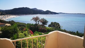Un balcon offrant une vue sur une plage, des montagnes et une végétation luxuriante.