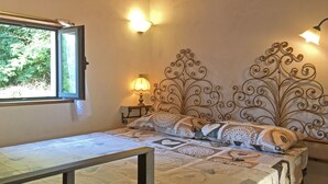 A bedroom with a bed, a nightstand with a lamp, a window, and a decorative metal headboard.