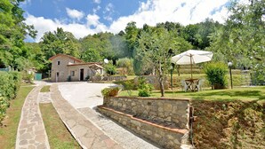A stone house with a patio, outdoor seating, and a stone wall.