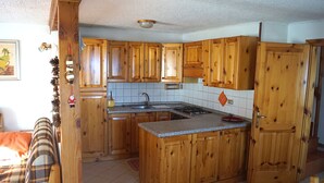 Een keuken met houten kastjes, een fornuis en een spoelbak.
