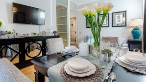 A modern living room with a dining area, a flat-screen TV, and a cozy seating arrangement. - Flourish Apartment with Grand Terrace inside Lucca City Centre (Lucca)