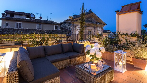 A rooftop terrace with a sofa, a table with candles, and a lantern. - Flourish Apartment with Grand Terrace inside Lucca City Centre (Lucca)