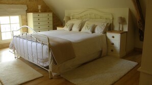 Ein Schlafzimmer mit Bett, Nachttischen, Fenster und Holzboden.