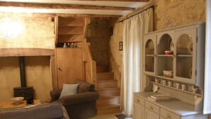 Ein gemütliches Wohnzimmer mit Kamin, einer Couch, einem Esstisch und einer Treppe, die in einen oberen Bereich führt.