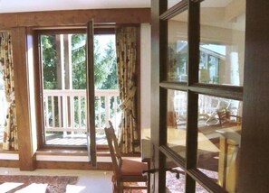 Une pièce dotée d’une grande porte-fenêtre coulissante donnant sur un balcon agrémenté d’une balustrade en bois.