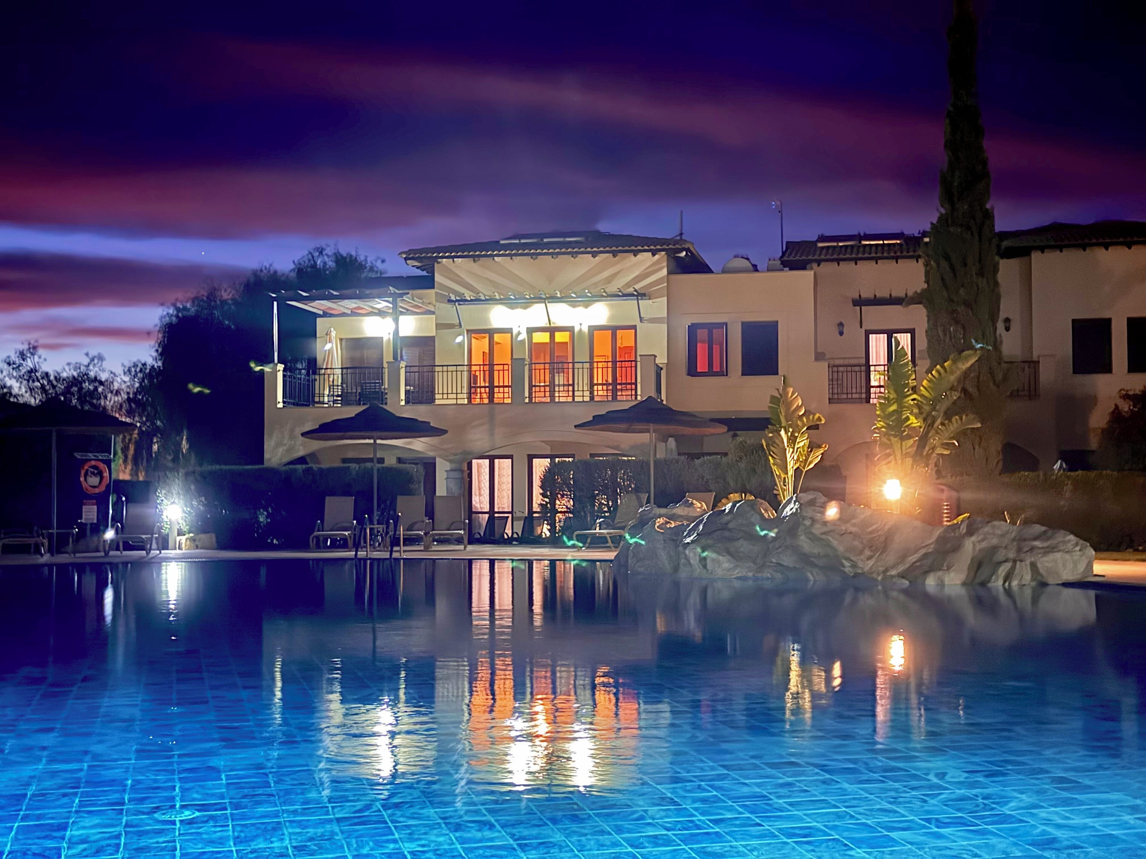A swimming pool with a reflection of a building with multiple windows and balconies.
