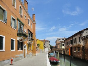 A narrow canal with buildings on either side, a fire hydrant on the sidewalk, and boats docked along the water. - Nati's House; Venice centre, in the lively district of Cannaregio, canal view (Venice)