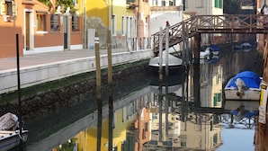 Ein Kanal mit Booten, eine Holzbrücke und Häuser mit Balkonen.