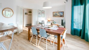 Een eethoek met een houten tafel en stoelen, een hanglamp en uitzicht op de kamer.