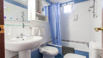 Un baño con lavamanos blanco, un bidé, inodoro y bañera.