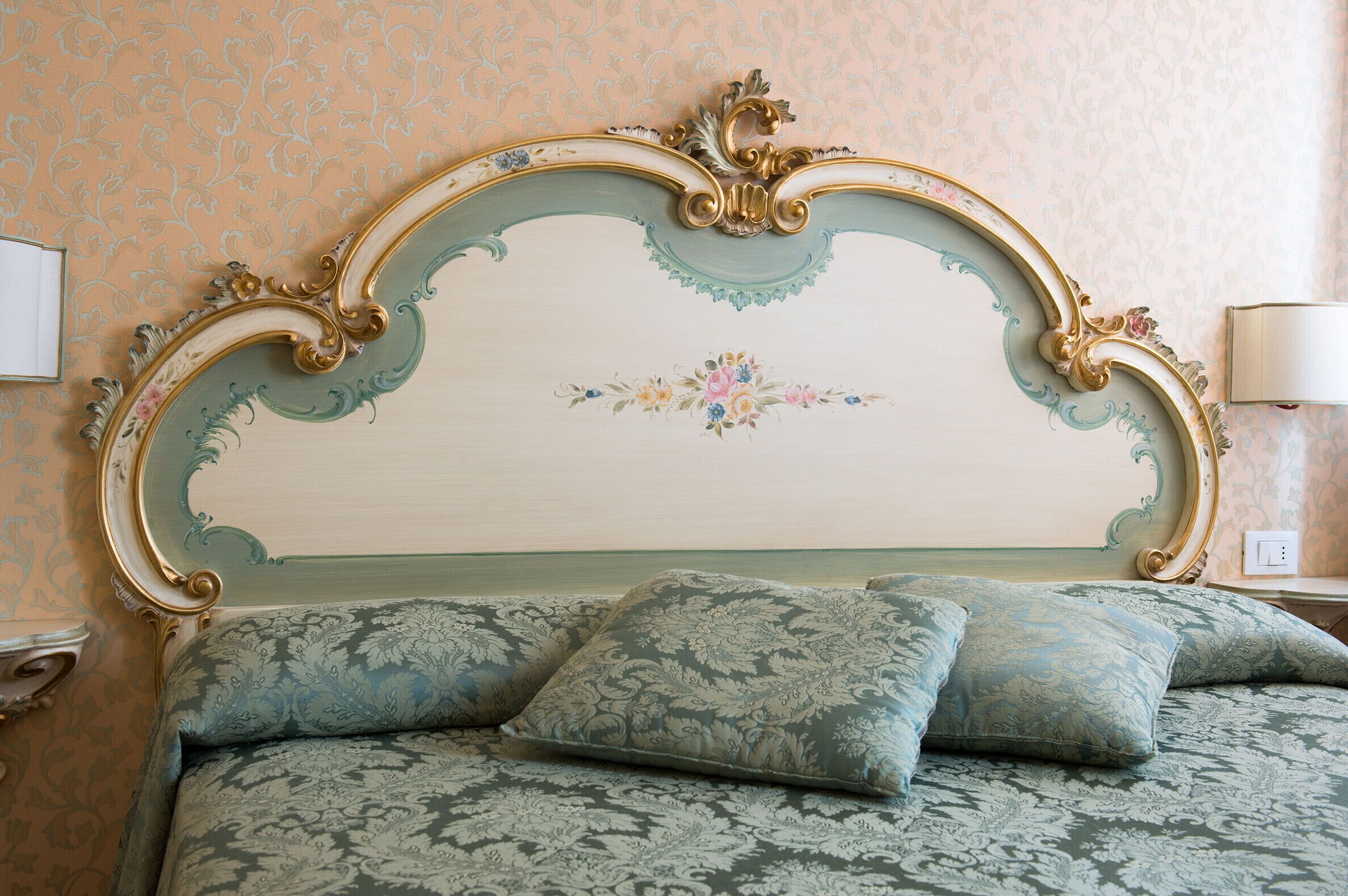 Una cama con un cabecero decorado y almohadas estampadas con motivos florales.