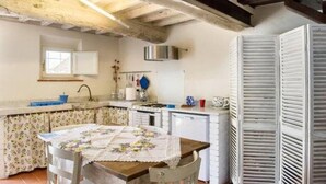 Una cocina rústica con vigas a la vista, una mesa de madera y un ventanal.
