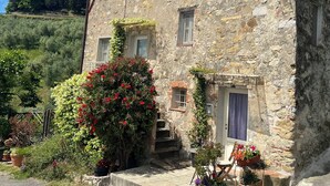 Un edificio de piedra de aspecto rústico, con una pequeña escalera que lleva a una puerta con un ventanal.