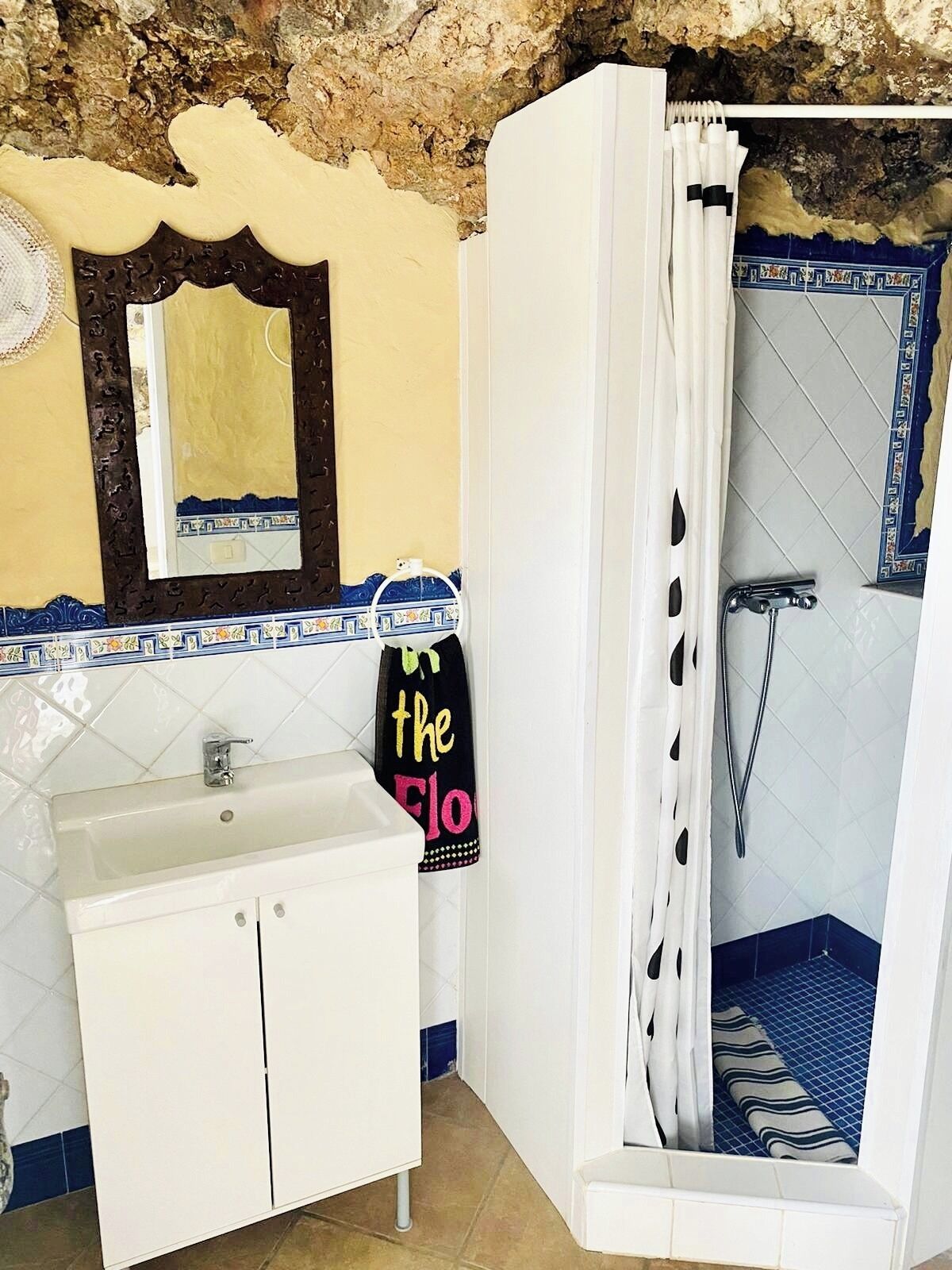A bathroom with a sink, mirror, and shower.