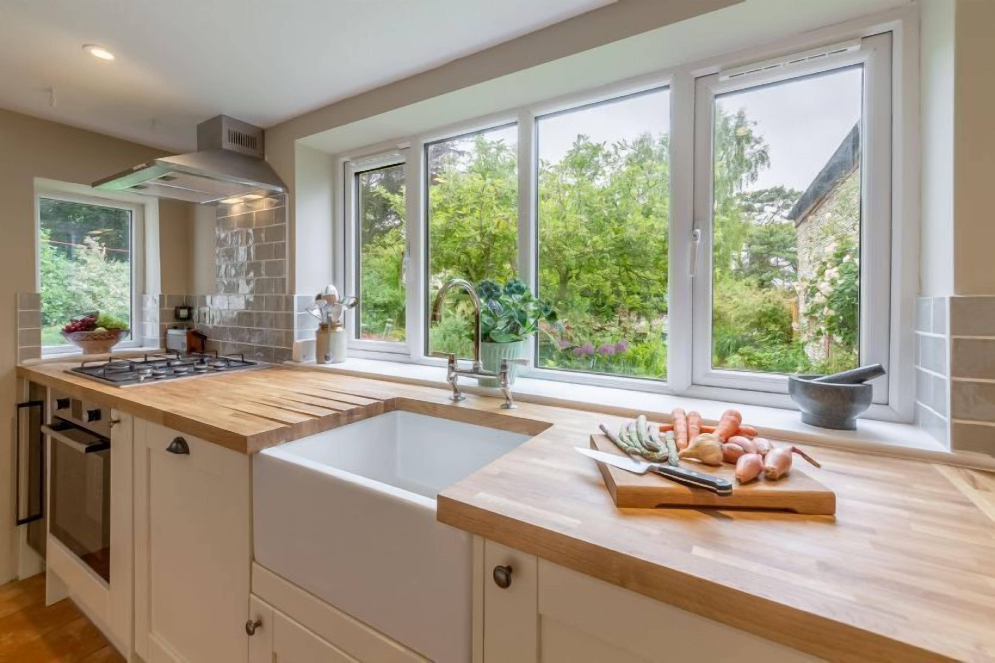 A modern kitchen with a large island, a built-in oven, and a window with a view of greenery.