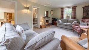 A cozy living room with a fireplace, a sofa set, and a plaid armchair. - Tusker House, Wells-next-the-Sea, Norfolk (Wells-next-the-Sea)