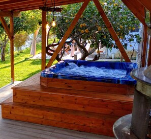 Un bain à remous avec des marches en bois et une pergola au-dessus.