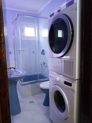 A compact bathroom with a built-in washing machine, a sink, and a shower enclosure. - The Elysian at Nicopolis exclusive outdoor jacuzzi  (preveza)