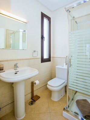 A bathroom with a sink, toilet, and glass shower enclosure.
