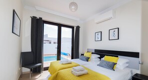 Una habitación de hotel con dos camas, vista a una piscina y una silla junto a la ventana.