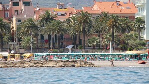 A coastal area with beach umbrellas, palm trees, and buildings with red-tiled roofs. - Penthouse on two levels at 20 meters from the sea in the center of Loano (Loano)