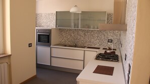 A compact kitchen with a built-in oven, a stainless steel sink, and a white countertop. - Penthouse on two levels at 20 meters from the sea in the center of Loano (Loano)
