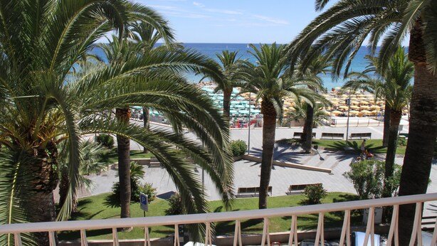 A view of a beach with palm trees, a parking area, and umbrellas. - Penthouse on two levels at 20 meters from the sea in the center of Loano (Loano)
