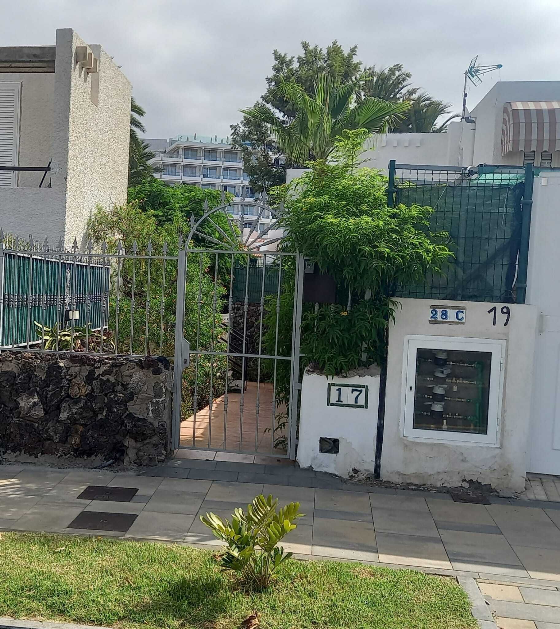 A gated residential area with numbered gates, a stone wall, and a paved pathway.
