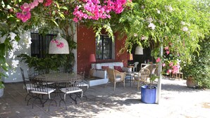 A patio with a round table and chairs, a sofa, and potted plants. - Modern villa on the beach, large private pool, BBQ, many flowers very quiet. (Almuñécar)