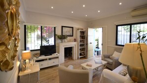 A living room with a fireplace, a television, and a bookshelf. - Modern villa on the beach, large private pool, BBQ, many flowers very quiet. (Almuñécar)