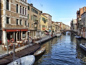 Un canal bordeado por edificios históricos, un puente y barcos amarrados a lo largo del agua.