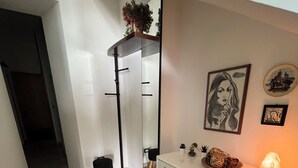 Un pasillo con un aparador blanco, un espejo y una planta colgante.