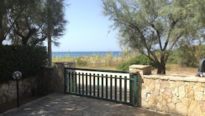 Un camino de piedra que lleva a una puerta con vista al mar.