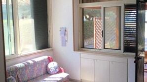 Una habitación con ventana, radiador, sofá y mesa.